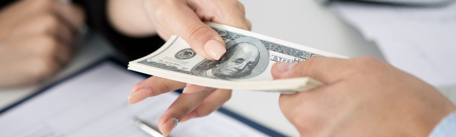 Woman taking batch of hundred dollar bills